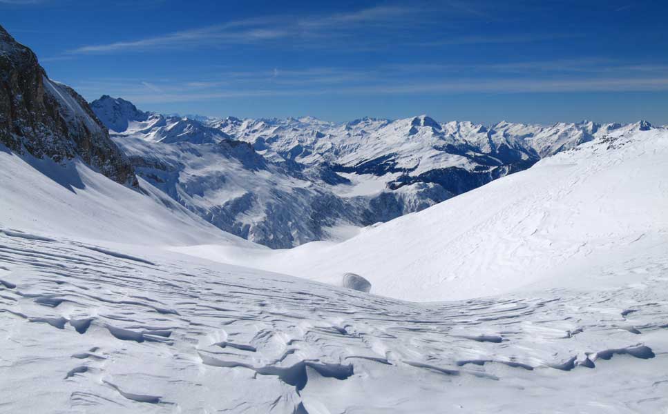 Le col versant sud. : Au premier plan le vallon sud qui mène au alpage de la Gitte (1665m) près du lac de la Gittaz.
On distingue en plein centre le lac de Roselend, et au loin sur l’horizon, le Pic de l’Etendard (3464m)