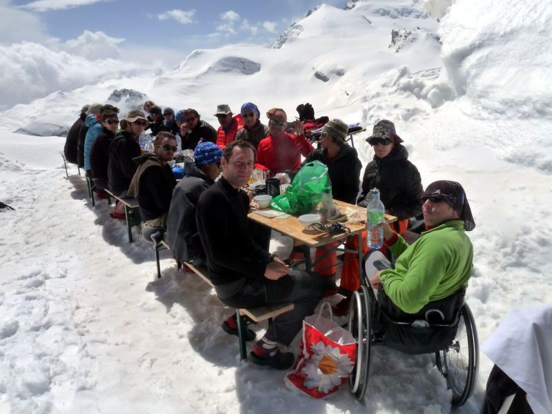 Après la descente ... : Après une excelente descente, et un dernier tractage pour Remonter au refuge Britannia, toute l'équipe profite d'un repos bien mérité autour d'une bonne table. En arrière plan, on devine la pente ravagée par le passage des 25 