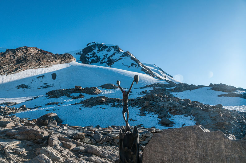 Piramide Vincent-2014 : Départ dans les derniers, pas le feu au lac vu le dégel tardif, sous la protection du Christ sur sa croix (pour les pôvres alpinistes en herbe ? qui en ch....t bien plus que les skieurs à la montée comme à la descente)